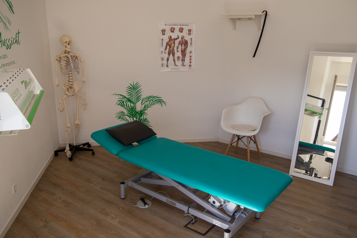 Behandlungsraum mit blauer Liege, Pflanzen und einem Anatomie-Modell